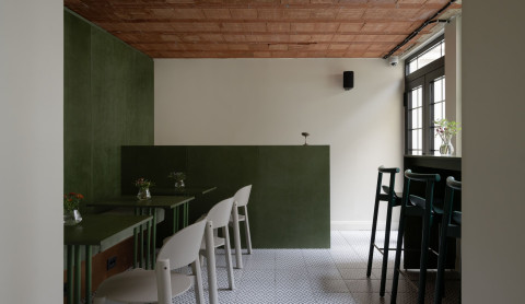 Large view of Fresca Deli with green plywood, exposed brick ceiling and casual seating