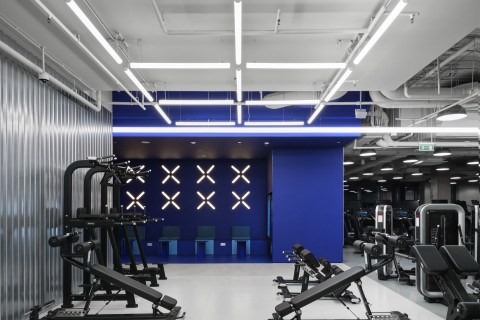 Open gym space at Gate-X Fitness Club with dark ceiling, metal textures and linear lights