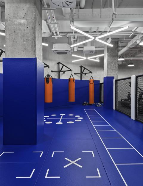 Vertical detail of the Gate-X Fitness Club corridor with concrete, glass and blue light