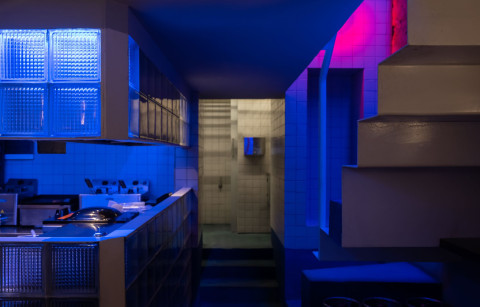 Semi-circular bar area with denim blue plaster and red lighting at KuKu Bar