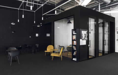 Mighty Buildings office coffee point with black meeting room volumes and yellow lounge chairs