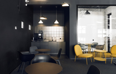 Mighty Buildings office cafeteria and lounge with black walls, yellow chairs and glass meeting room