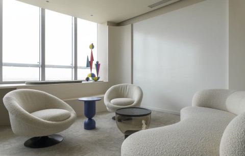 Private office lounge with marker wall, sculptural art and upholstered seating