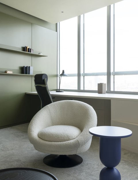 Private office workspace by panoramic windows with lounge chair and blue side table