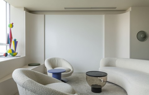 Private office lounge with curved sofa, armchairs and colorful sculptural artwork