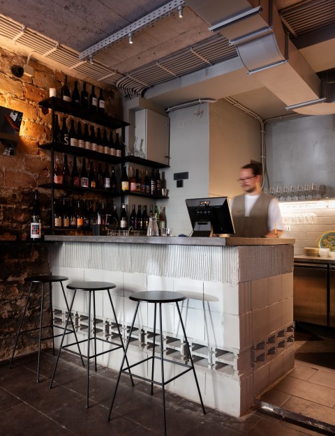 Wine shelf detail at Proces Wine bar with focused lighting and raw material palette