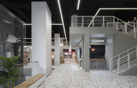 Long corridor perspective in Siesta Shopping Center with white walls and terracotta accents