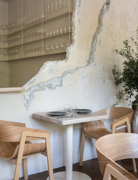 Textured wall seating area at Stories restaurant with wooden chairs and globe lamp
