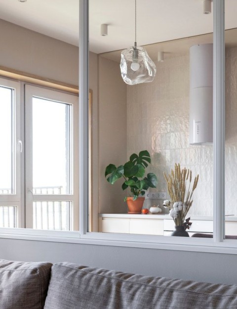 Terra Apartment sofa beside an interior window looking into the kitchen