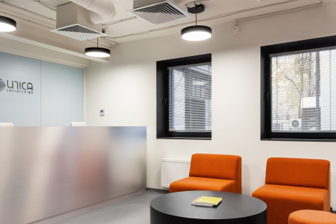 UNICA Office reception lounge with orange seating, black-framed windows and branded wall