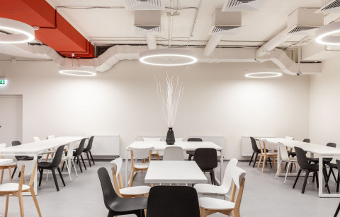 UNICA Office dining area with white tables, circular lights and terracotta ceiling accent