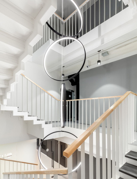 UNICA Office stairwell with white railings and suspended ring lights