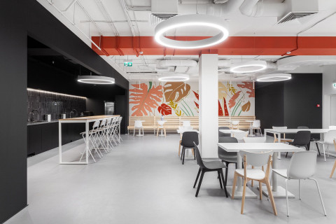 UNICA Office cafeteria with black bar, white tables and botanical wall mural